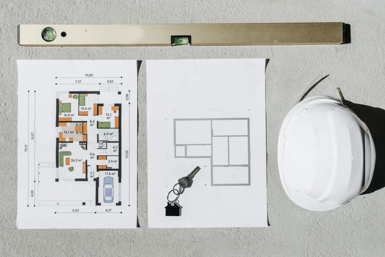 Construction plans, a spirit level, a hard hat and a key arranged for project planning