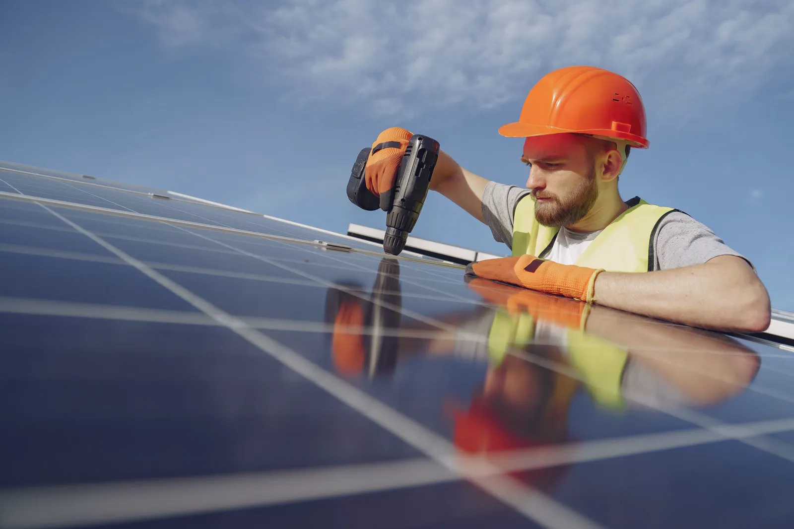 A solar installer using a drill while fitting a panel